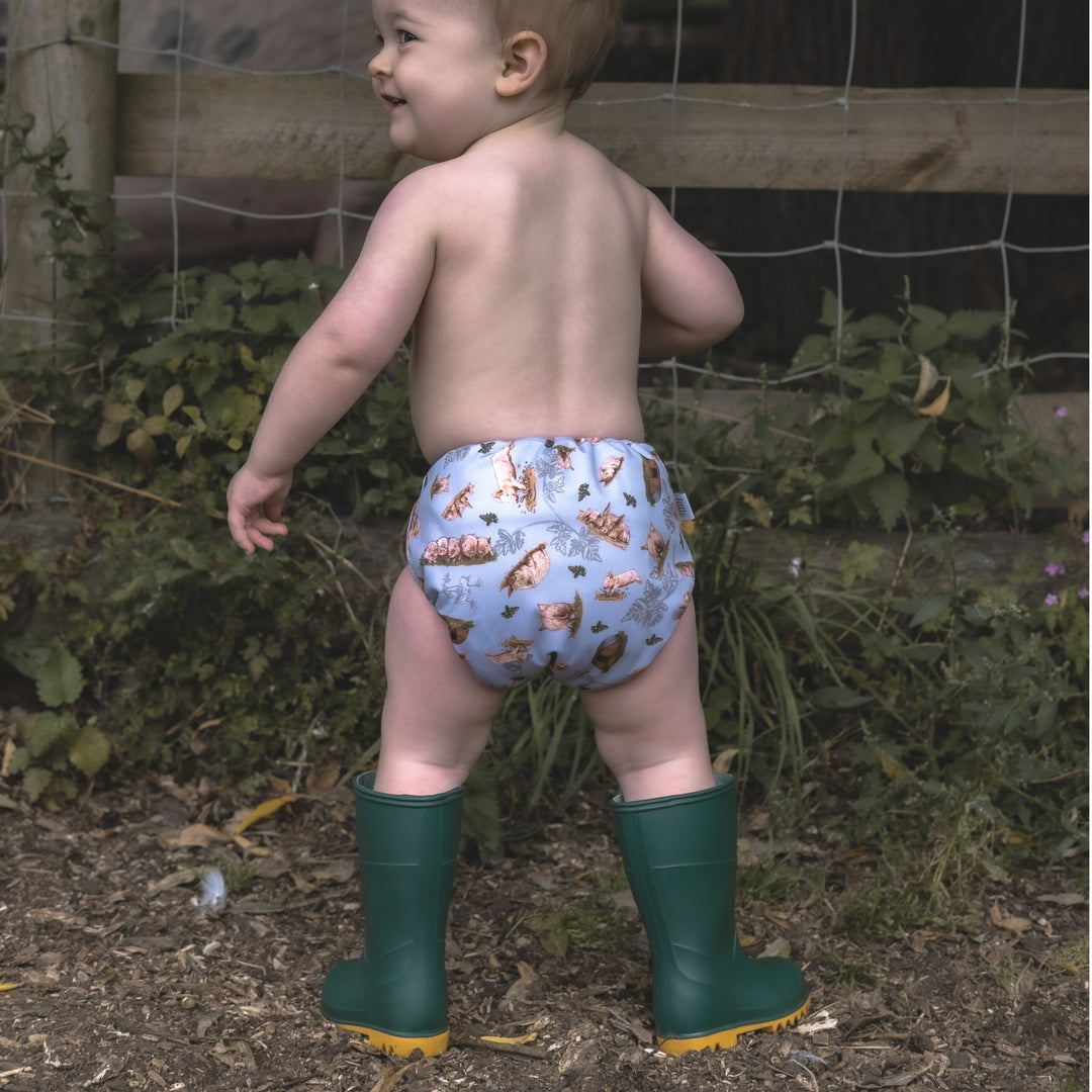 Baby wearing Onesize Reusable Pocket Nappy with Pig Print by LittleLamb and Wellington Boots#color_sow-in-love